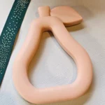 Peach Silicone Pear Baby Teether – Easy-Grasp Silicone Teether for Pain-Free Teething on a green glass base.