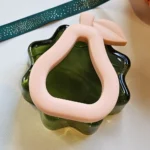 Peach Silicone Pear Baby Teether – Easy-Grasp Silicone Teether for Pain-Free Teething on a green glass base.