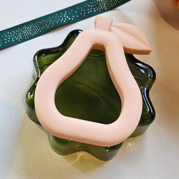 Peach Silicone Pear Baby Teether – Easy-Grasp Silicone Teether for Pain-Free Teething on a green glass base.