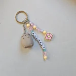 Close up of an Australian-made, sustainable Pusheen keychain featuring a pastel pink and yellow flower charm and recycled acrylic beads.