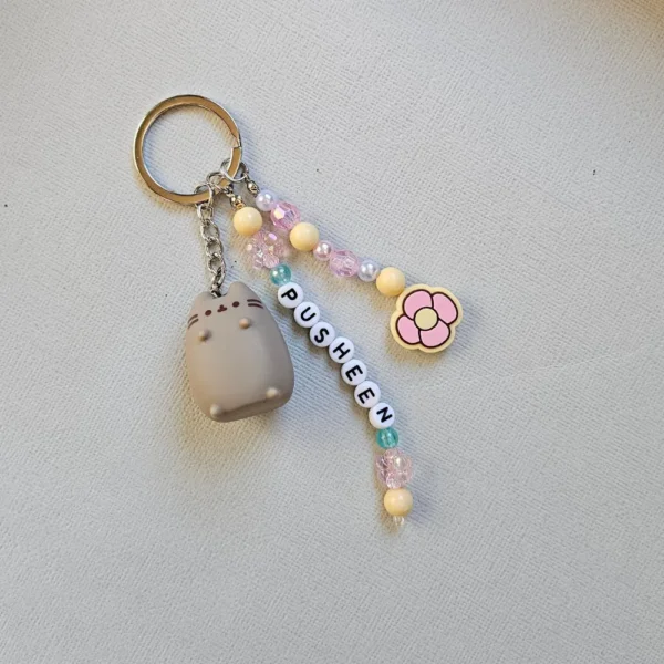 Close up of an Australian-made, sustainable Pusheen keychain featuring a pastel pink and yellow flower charm and recycled acrylic beads.