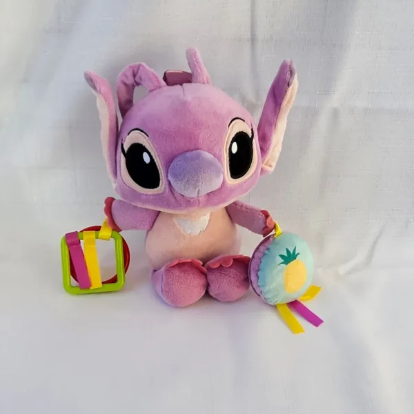 Plush Disney Baby Angel activity toy for infants, featuring a soft purple character doll with hanging plastic teething rings and a round plush pineapple rattle disc with satin tags.